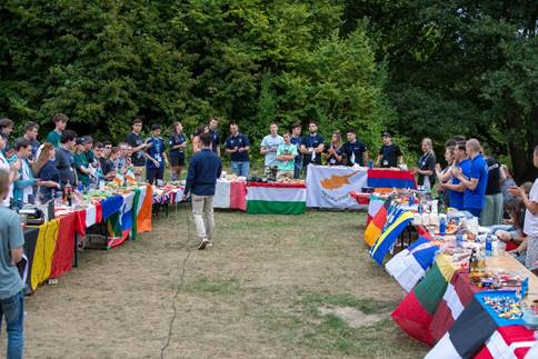 A group of people standing around tables with flags
AI-generated content may be incorrect.